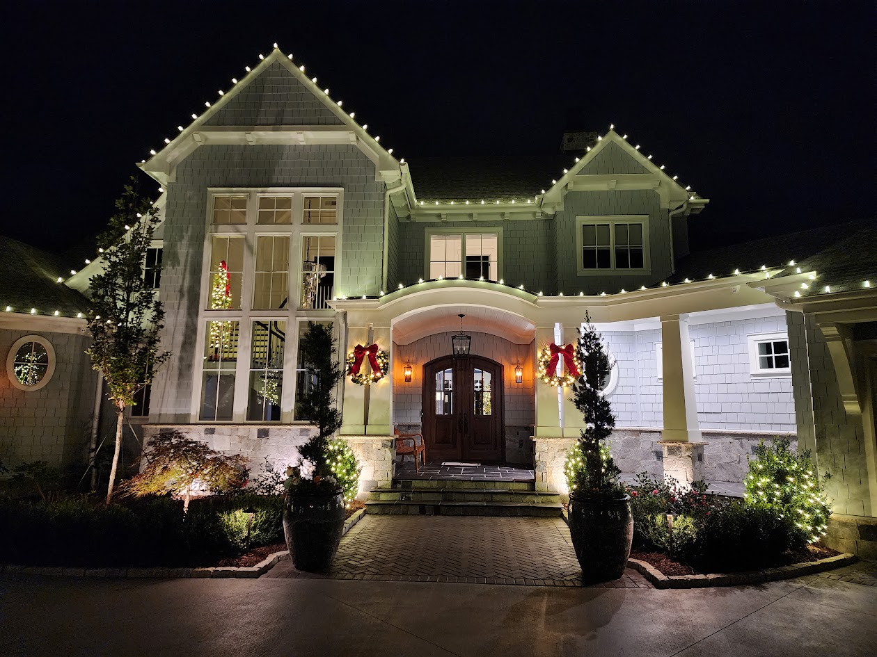 Warm-white roofline lighting, wreaths and greenery on a large estate entrance